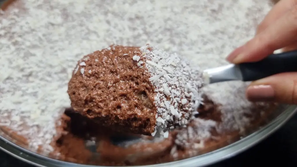 close up de mão de mulher pegando uma porção de mousse de chocolate com menta e cobertura de coco ralado