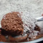 close up de mão de mulher pegando uma porção de mousse de chocolate com menta e cobertura de coco ralado