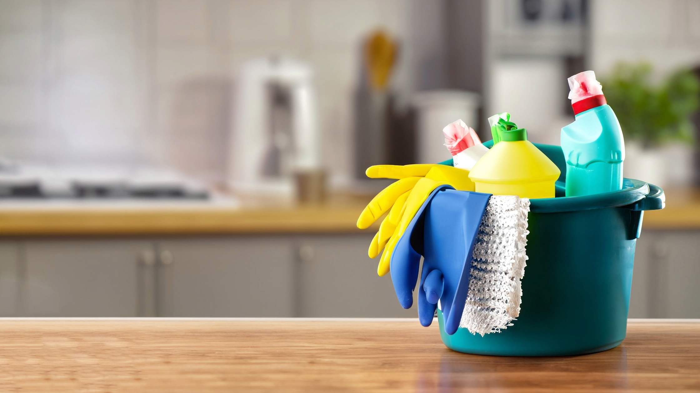 um balde com produtos de limpeza em cima de uma bancada para ilustrar coisas que você deve limpar todos os dias na cozinha