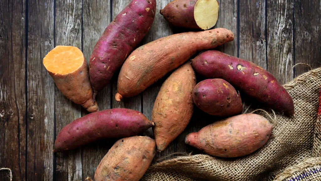 foto de várias batatas em uma mesa de madeira - como cozinhar batata doce