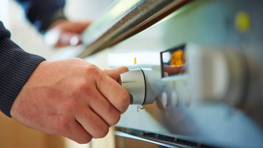 foto close up da mão de um homem ajustando a temperatura do forno para cozinhar em fogo alto, médio ou baixo